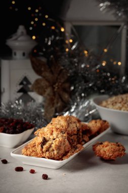 Ev yapımı yulaf ezmeli kurabiye ve Noel süslemeleri olan bir masada kuru üzüm..