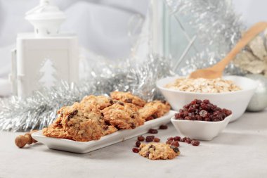 Ev yapımı yulaf ezmeli kurabiye ve Noel süslemeleri olan bir masada kuru üzüm..