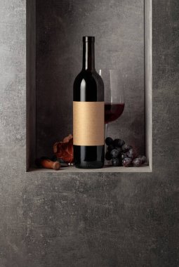 Mavi üzümlü bir şişe ve bir bardak kırmızı şarap. Şişede eski boş etiket var. Boşluğu kopyala.