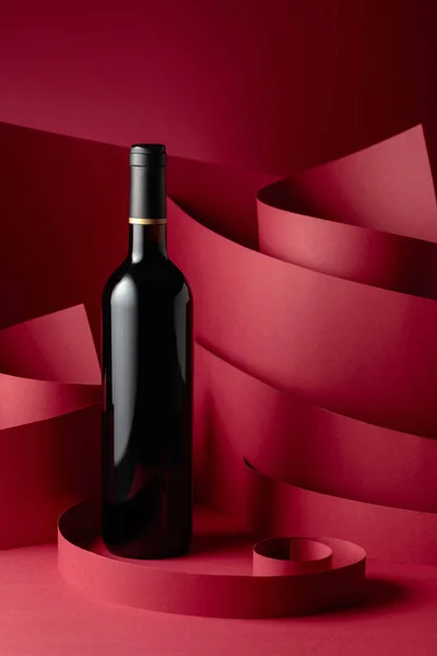 赤い背景に赤ワインの未開封のボトル — ストック写真