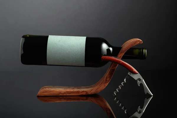 黒の反射的な背景に木製のボトルホルダーに空のラベルを持つ赤ワインのボトル スペースのコピー — ストック写真