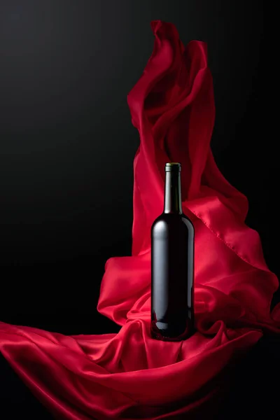 红葡萄酒瓶 底色为黑色 红布飘扬 — 图库照片