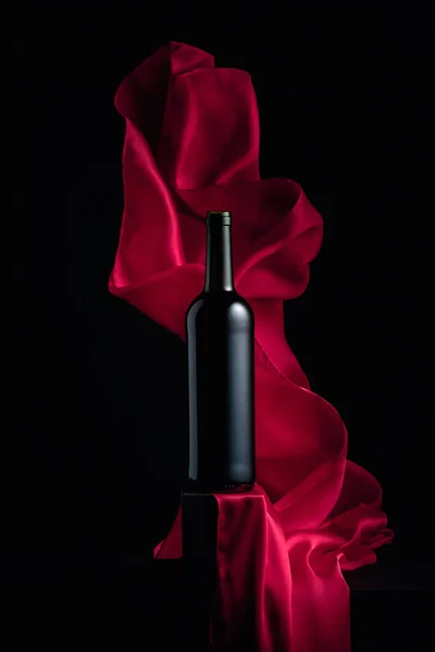 Butelka Czerwonego Wina Czarnym Tle Trzepotaniem Czerwonej Tkaniny — Zdjęcie stockowe