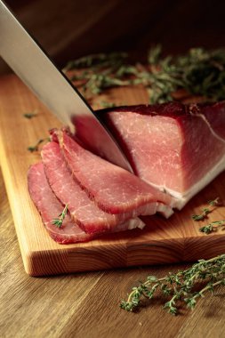 Tahta kesme tahtasının üzerinde kekik ile kurutulmuş domuz filetosu..