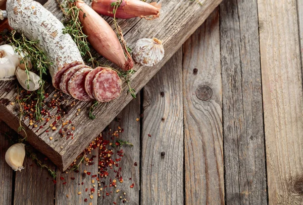 Traditional dry-cured sausage with thyme, garlic, onion, and spices. Dry-cured sausage on a old wooden table. Copy space.