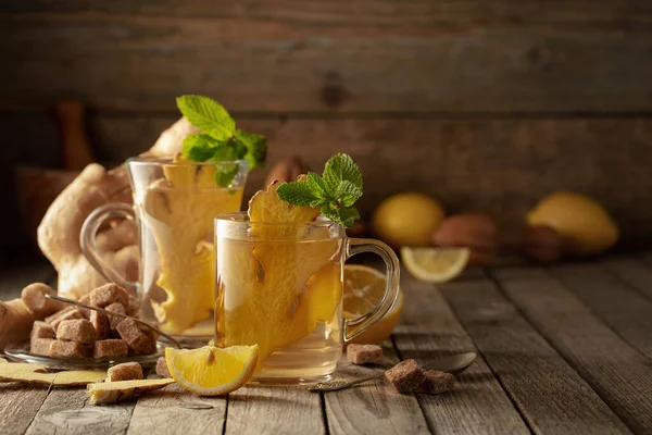 Malzemeli zencefil çayı. Zencefil, limon, nane ve esmer şeker eski ahşap bir masada.