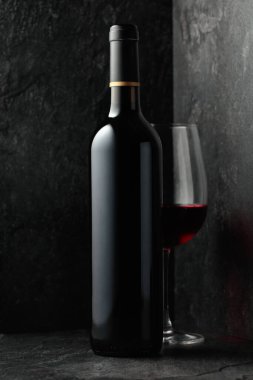 Siyah taşlı arka planda bir şişe kırmızı şarap..