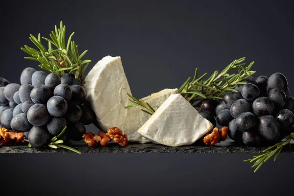 Kaas Camembert Met Walnoten Blauwe Druiven Rozemarijn Een Zwarte Achtergrond — Stockfoto
