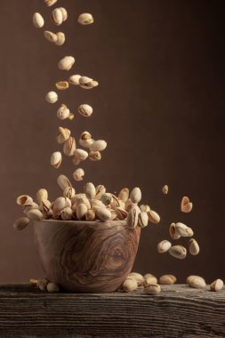 Uçan tuzlu şam fıstığı. Tahta bir kasede kurutulmuş fındık. Boşluğu kopyala.