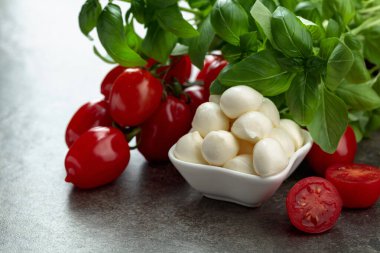 Eski bir taş masada fesleğen ve domatesli Mozzarella peyniri. Geleneksel İtalyan atıştırması.