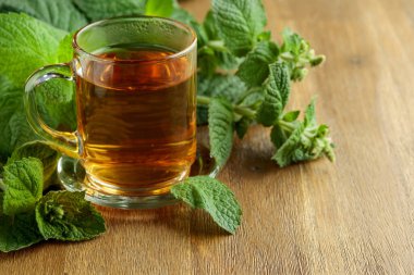 Mint tea in glass on a wooden table.