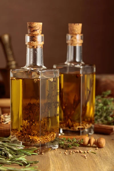 Bottles of olive oil with herbs and spices. Olive oil and kitchen utensils on a wooden table.