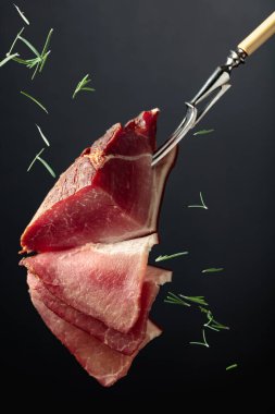 Kurutulmuş domuz filetosu. Siyah arka planda biberiye serpiştirilmiş..