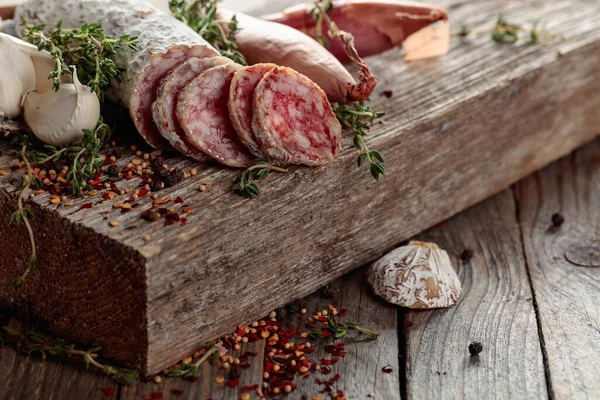 Traditional dry-cured sausage with thyme, garlic, onion, and spices. Dry-cured sausage on a old wooden table.