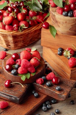 Yapraklı taze böğürtlen. Çilek, ahududu, böğürtlen ve kirazlar eski ahşap bir masada.. 