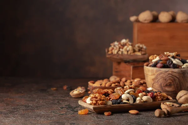 Mix of nuts and raisins on a brown rustic background. Presented raisins, walnuts, hazelnuts, cashews, pecans, and almonds.