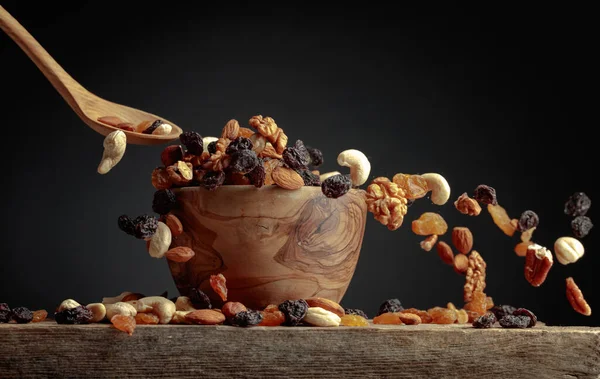 Flying dried fruits and nuts. The mix of dried nuts and raisins in a wooden bowl. Copy space.