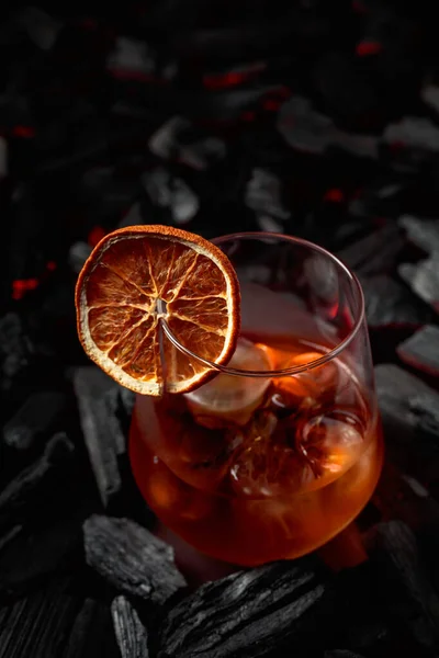 Old-fashioned cocktail with ice and dried orange slice.