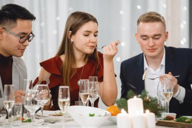 Şenlik masasında şampanya kadehleriyle gülümseyen, restoranda konuşan üç arkadaş. Seçici odak, bulanık ışıklar.