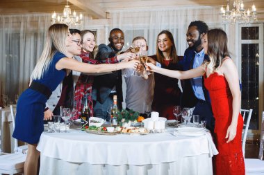 Genç çokuluslu insanlar festivalde şampanyayla bardakları boğarken eğleniyorlar. Seçici odak, bulanık ışıklar.