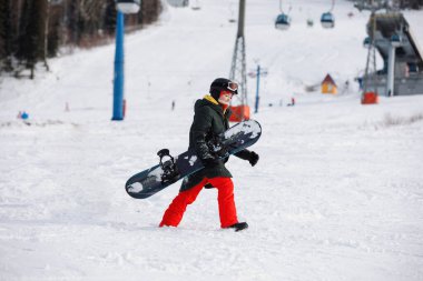 Kadın snowboardcu karlı dağda yürüyor. O bir maske, kask, gözlük ve kırmızı pantolon giyiyor. Sağlıklı bir yaşam tarzı. Spor konsepti. Seçici odak.