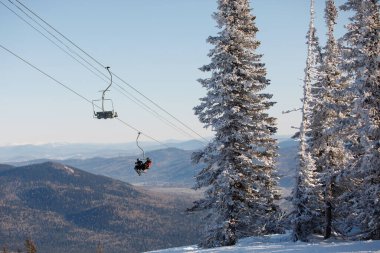 Mavi dağların arka planında hareket halindeki kayaklı teleferik koltuğu. Sağlıklı bir yaşam tarzı. Spor konsepti. Seçici odak.