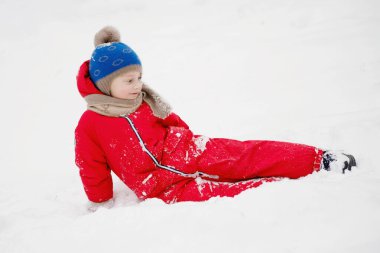 Parkta örgü şapkalı ve kırmızı ceketli bir çocuğun portresi. Seçici odak.