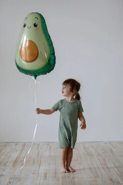 Çocuk Kısımda Bebek Tulumunun Içindeki Avokado Şekilli Balonla Eğleniyor — Stok fotoğraf