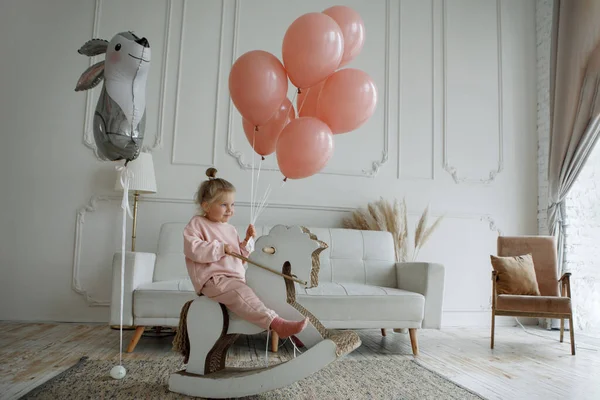 Pieni Tyttö Vaaleanpunainen Ilmapalloja Istuu Lelu Hevonen Sisustus — kuvapankkivalokuva