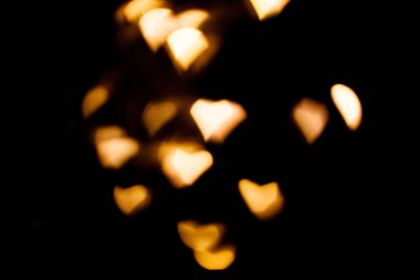 Siyah arka planda parlak sarı bulanık kalp ışıkları. İşlem sonrası fotoğraflar ve tasarım için Bokeh.