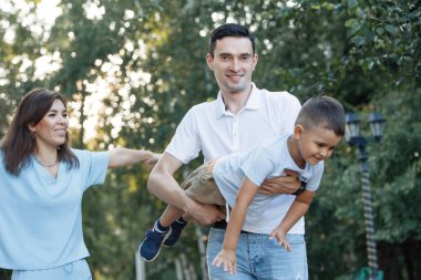 Baba oğluyla bir yaz parkında eğleniyor. Seçici odaklanma, bulanık arkaplan. Mutlu bir çocukluk. Ebeveyn bakımı.