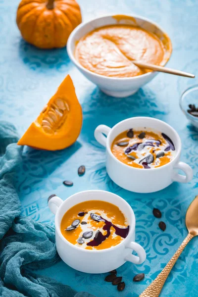 ココナッツミルク カボチャ油と青い背景に種と自家製のカボチャのスープ — ストック写真