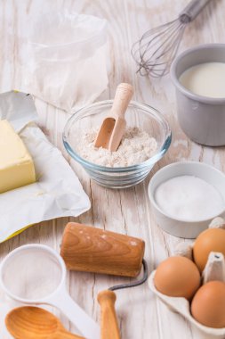 Ahşap arka planda pişirmek ve pişirmek için çeşitli yemek malzemeleri ve mutfak aletleri.