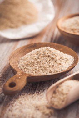 Ahşap masadaki ahşap kasede bir yığın Psyllium kabuğu. Psilyum kabuğu, Hindistan 'da bulunan bitki yumurtası bitkisinin tohumlarından elde edilen liftir..