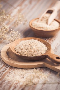 Ahşap masadaki ahşap kasede bir yığın Psyllium kabuğu. Psilyum kabuğu, Hindistan 'da bulunan bitki yumurtası bitkisinin tohumlarından elde edilen liftir..