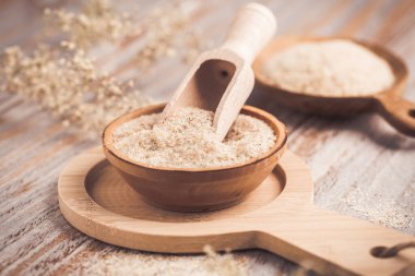 Ahşap masadaki ahşap kasede bir yığın Psyllium kabuğu. Psilyum kabuğu, Hindistan 'da bulunan bitki yumurtası bitkisinin tohumlarından elde edilen liftir..