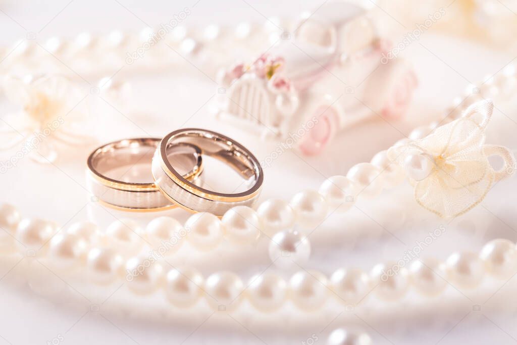 Wedding still life with golden rings and pearl necklace in white