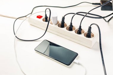 Many chargers plugged into multiple socket. Concept of overloading and energy costs
