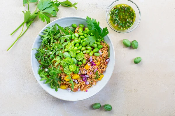 Healthy couscous salad with edamame beans, rucola and cucamelon (Mexican miniature watermelon), with lemon and herbs dressing