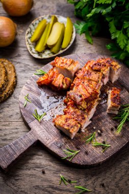 Roasted pork belly with crust,  pickles and bread on cutting board