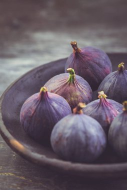 Tahta arka planda bir kasede taze organik incir.