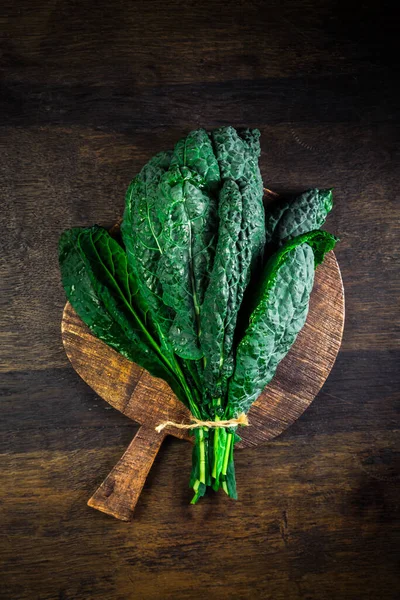 Palm kale, black cabbage - Cavolo nero black curly kale. Nero di Toscana (Brassica oleracea) on cutting board