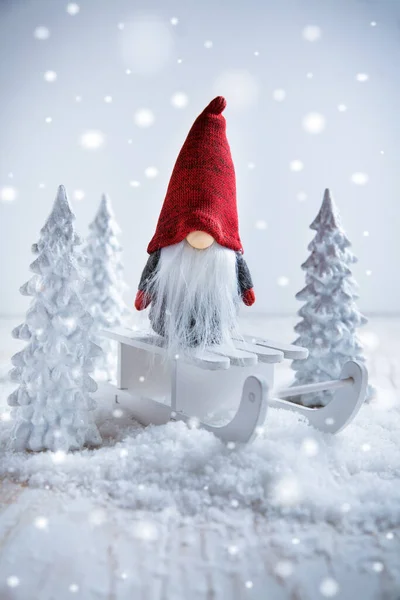 かわいいクリスマスのノームは白い木と冬の国のそりに座っています — ストック写真