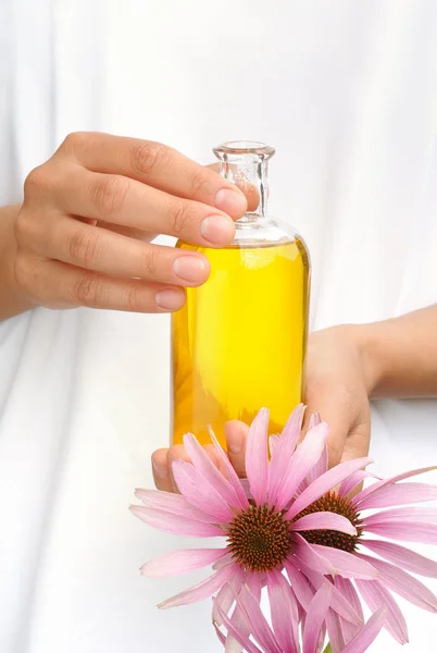 Mains de jeune femme tenant de l'huile essentielle et des fleurs de cajou fraîches — Photo