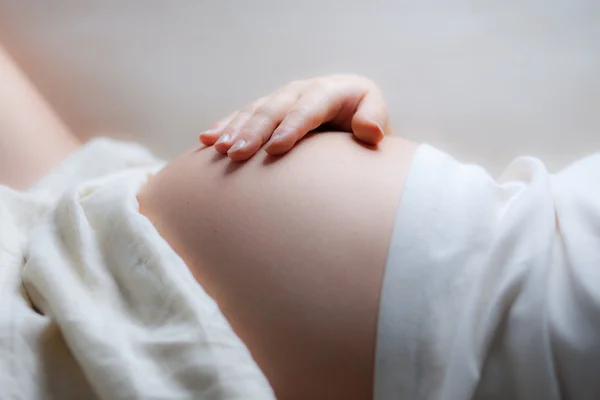 Беременная женщина держит живот рукой. — стоковое фото