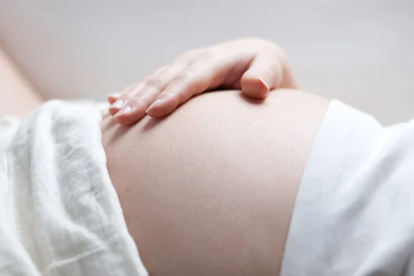 Pregnant woman holding her belly with her hand — Stock Photo, Image