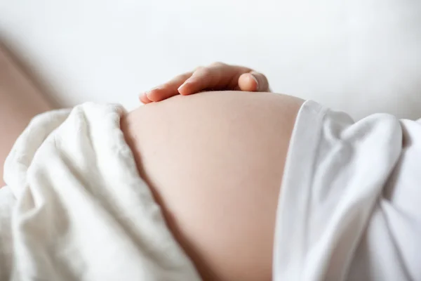 Беременная женщина держит живот рукой. — стоковое фото