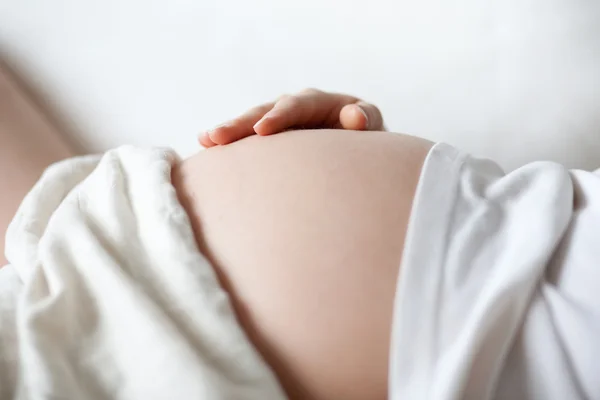 Pregnant woman holding her belly with her hand Stock Picture