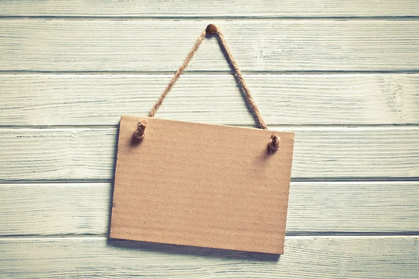 Paper board hanging on wooden wall — Stock Photo, Image