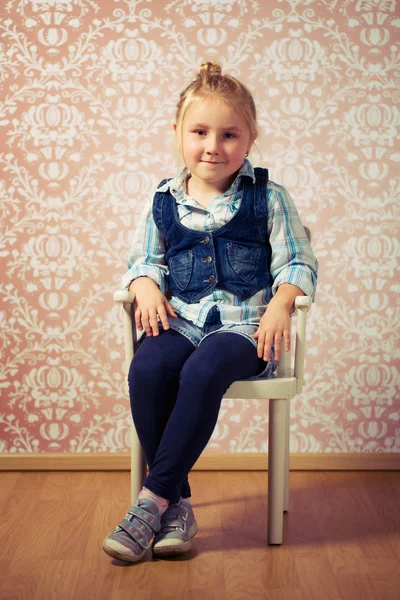 Liten flicka sitter på en stol — Stockfoto